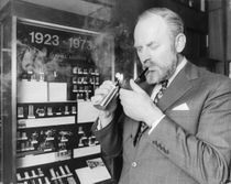 14 Mai 1973 : Richard Dunhill, vice-président de Dunhill et petit fils de son fondateur, allumant sa pipe devant une vitrine retraçant l'évolution des briquets Dunhill. (Photo par Ian Showell/Keystone).
